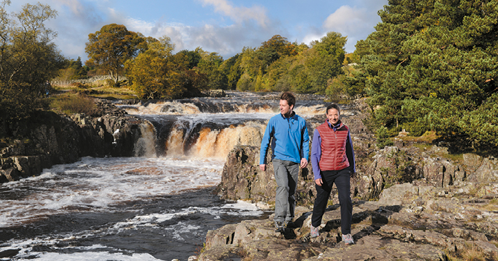 couple walking past low force waterfall